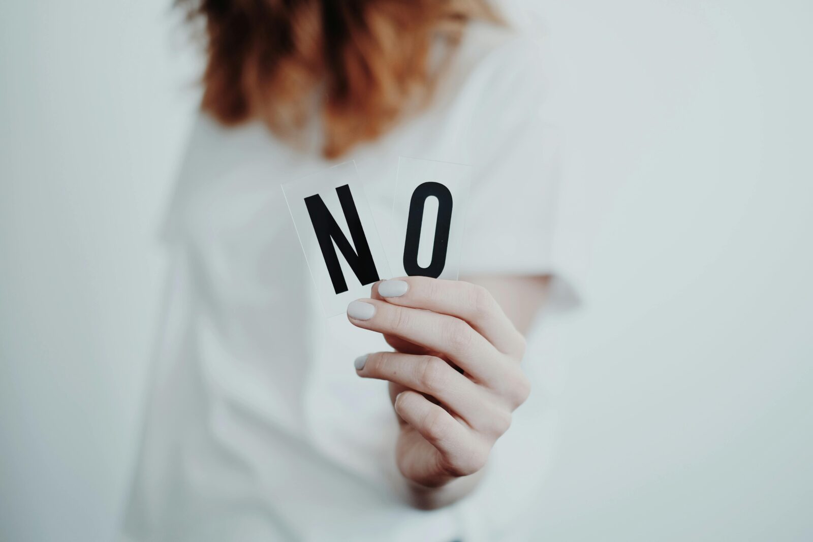 Frau hält ein Schild mit dem Wort NO in der Hand – Symbol für Grenzen setzen und das Leben selbstbestimmt gestalten